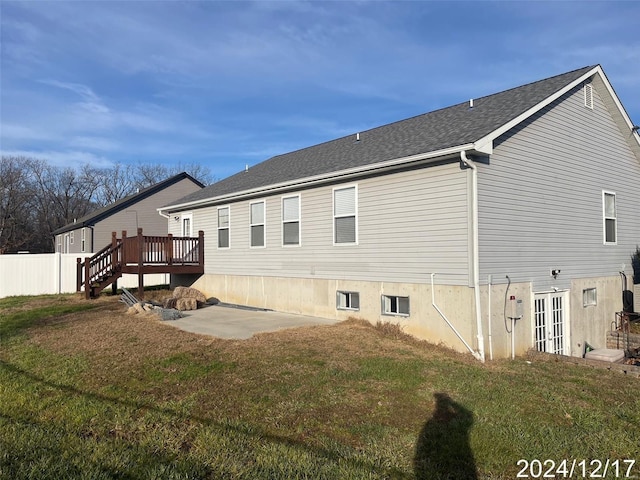 rear view of property featuring a lawn, a deck, and a patio