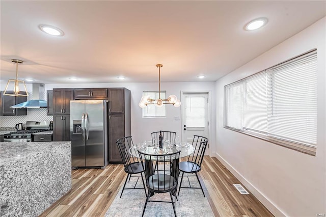 dining area with light hardwood / wood-style flooring and a chandelier