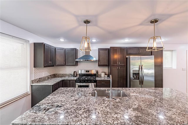 kitchen with pendant lighting, dark brown cabinets, light stone counters, and stainless steel appliances