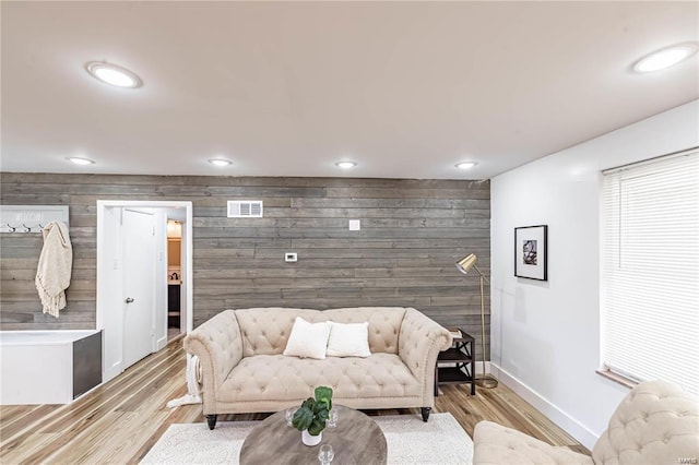 living room featuring wood walls and light hardwood / wood-style flooring