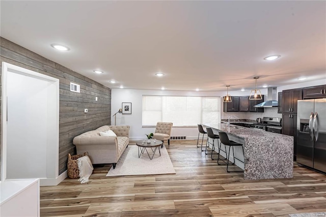 living room featuring wood walls, sink, and light wood-type flooring