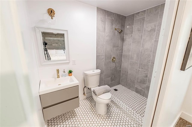 bathroom featuring tiled shower, vanity, toilet, and tile patterned flooring