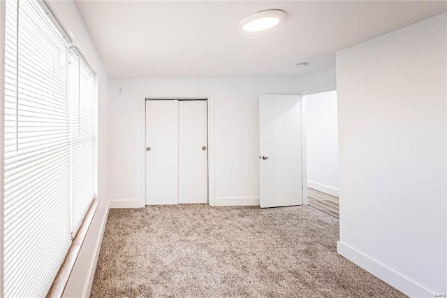 unfurnished bedroom with light colored carpet and a closet