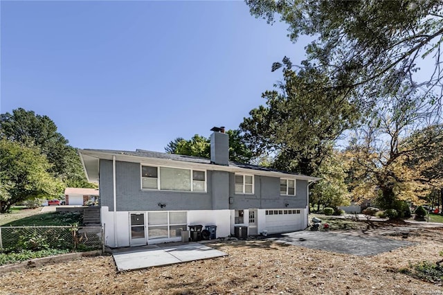 rear view of property featuring a garage, a patio, and central AC