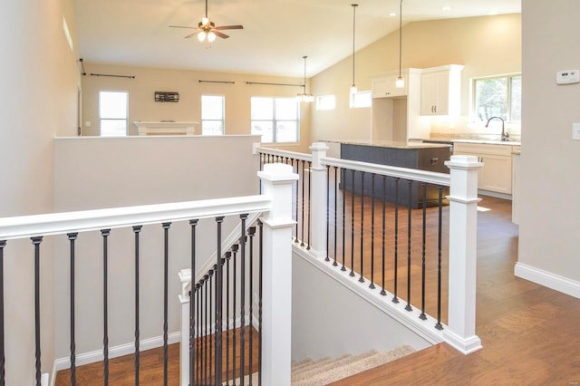 stairs featuring baseboards, high vaulted ceiling, wood finished floors, and a ceiling fan