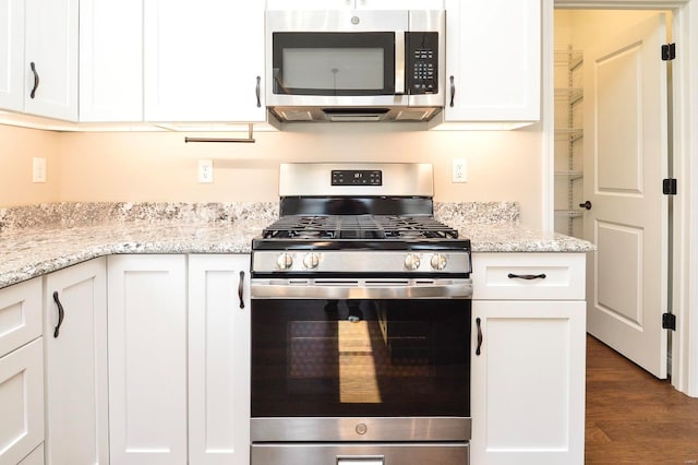 kitchen featuring light stone countertops, dark wood-type flooring, appliances with stainless steel finishes, and white cabinetry