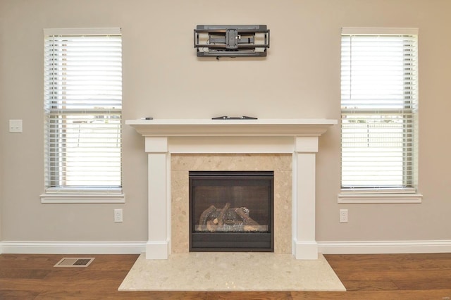 room details with visible vents, a fireplace, baseboards, and wood finished floors