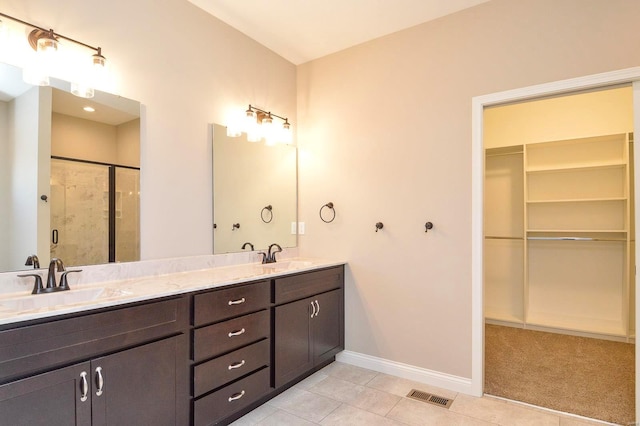 bathroom featuring visible vents, a shower stall, a walk in closet, and a sink