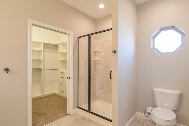 full bath featuring tile patterned flooring, a spacious closet, toilet, and a stall shower