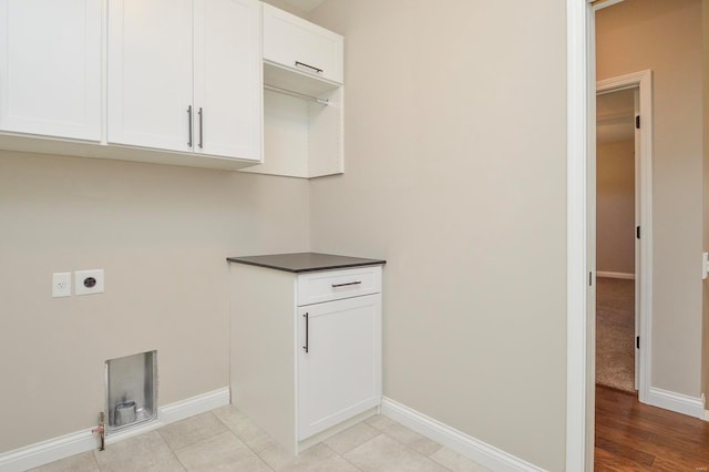 laundry room with light tile patterned flooring, cabinet space, electric dryer hookup, and baseboards