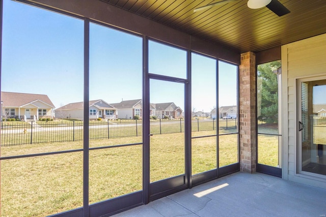 unfurnished sunroom featuring wood ceiling, a residential view, and ceiling fan