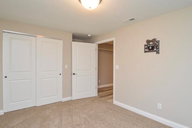 unfurnished bedroom with baseboards, visible vents, carpet floors, and a closet