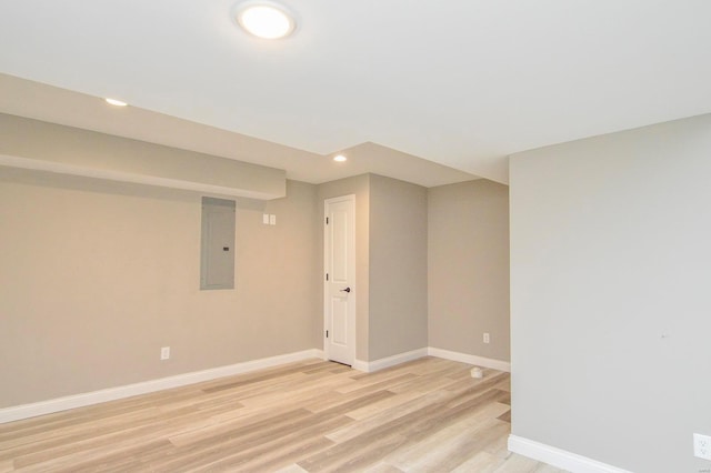 unfurnished room with light wood-style flooring, electric panel, recessed lighting, and baseboards