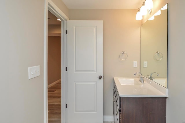 bathroom with vanity, wood finished floors, and baseboards