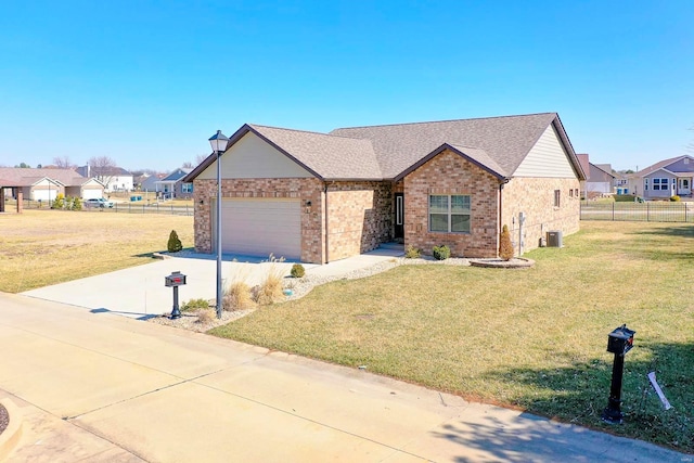 view of front of home with a front yard, fence, an attached garage, concrete driveway, and brick siding