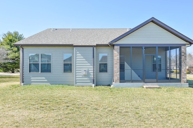 back of property featuring a lawn, a shingled roof, and a sunroom