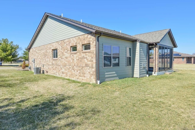 view of home's exterior featuring a yard, brick siding, central AC unit, and a sunroom