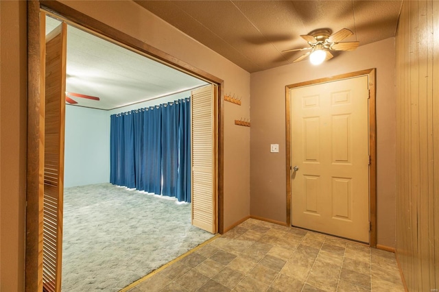 entryway with light carpet, wooden walls, ceiling fan, and a textured ceiling