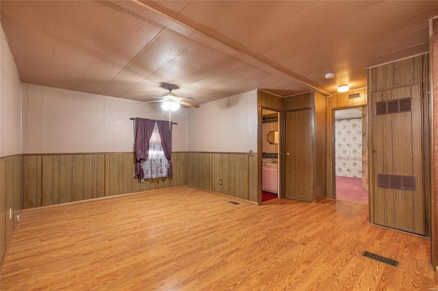 spare room featuring ceiling fan, wood walls, and wood-type flooring