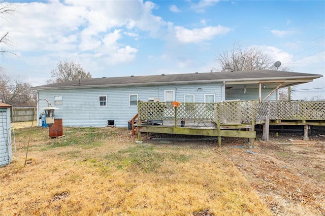 rear view of property with a wooden deck and a lawn