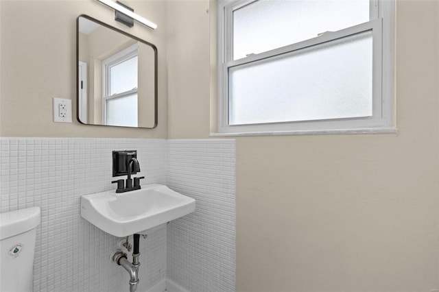 bathroom featuring toilet and tile walls