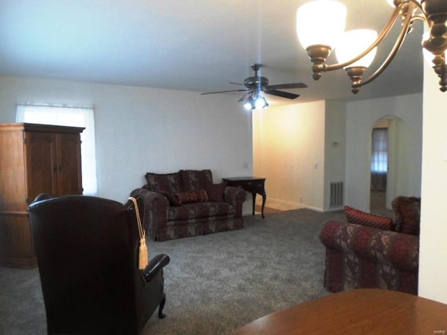 carpeted living room with ceiling fan with notable chandelier