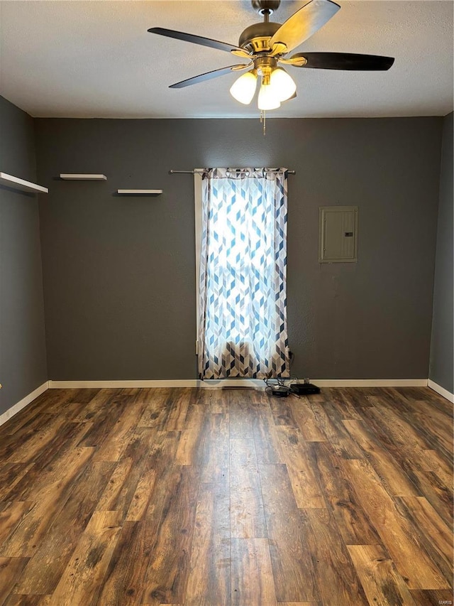 empty room with ceiling fan, dark hardwood / wood-style floors, electric panel, and a textured ceiling