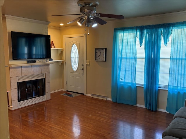 living room with ornamental molding, ceiling fan, a healthy amount of sunlight, a fireplace, and hardwood / wood-style floors