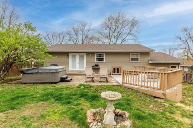 back of property with a hot tub, a lawn, a patio area, and a wooden deck