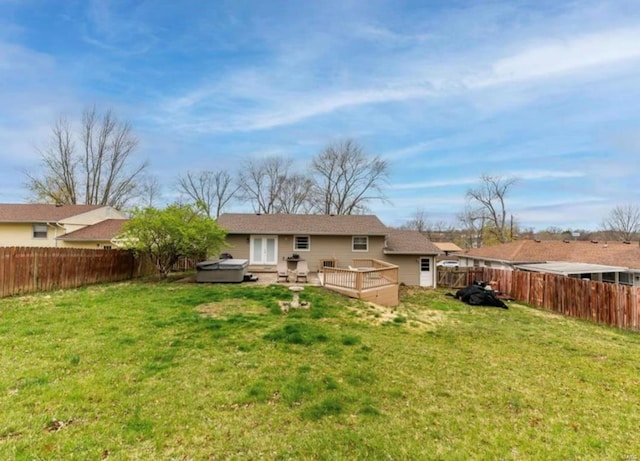 rear view of property with a yard, a hot tub, and a deck