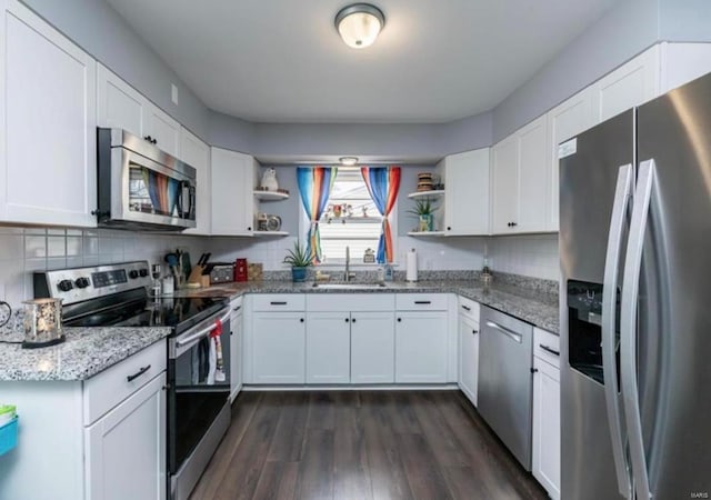 kitchen featuring white cabinetry, sink, light stone counters, and appliances with stainless steel finishes