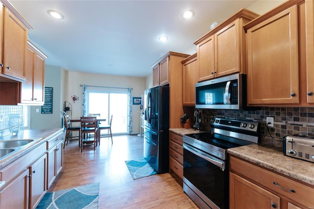 kitchen featuring backsplash, light wood-type flooring, and stainless steel appliances