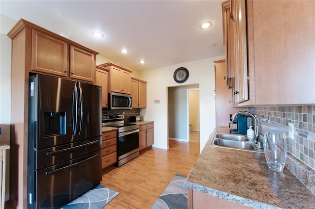 kitchen featuring backsplash, sink, stainless steel appliances, and light hardwood / wood-style flooring