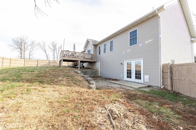 back of property featuring a deck, a yard, and french doors