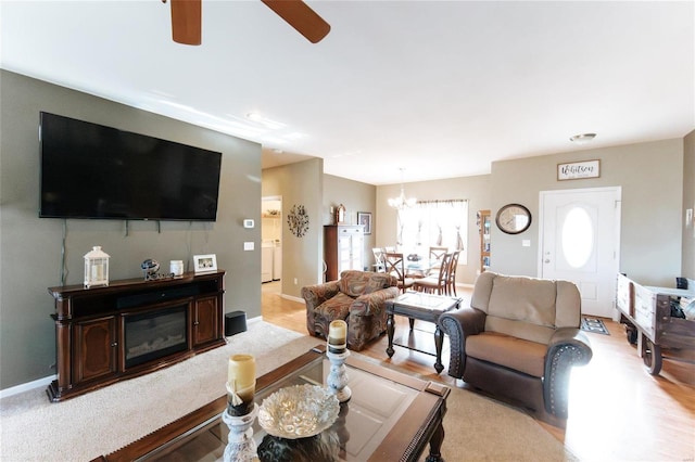 living room with ceiling fan with notable chandelier, light hardwood / wood-style flooring, and a healthy amount of sunlight