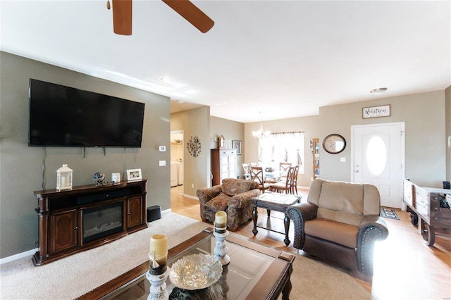 living room with ceiling fan with notable chandelier and light wood-type flooring