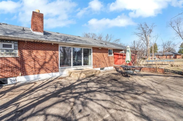 rear view of house with a trampoline and a patio