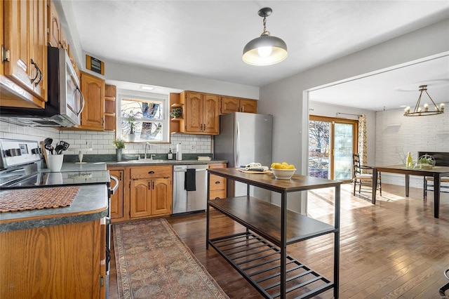 kitchen with stainless steel appliances, dark hardwood / wood-style floors, decorative light fixtures, and sink