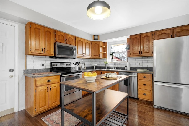 kitchen featuring appliances with stainless steel finishes, dark hardwood / wood-style floors, sink, and backsplash