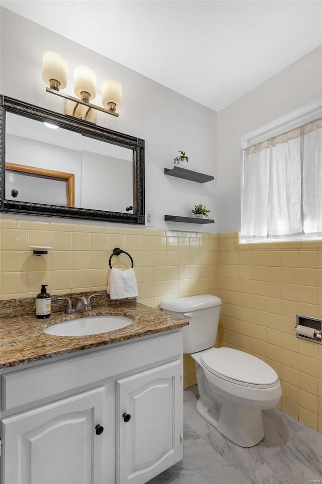 bathroom with vanity, toilet, and tile walls