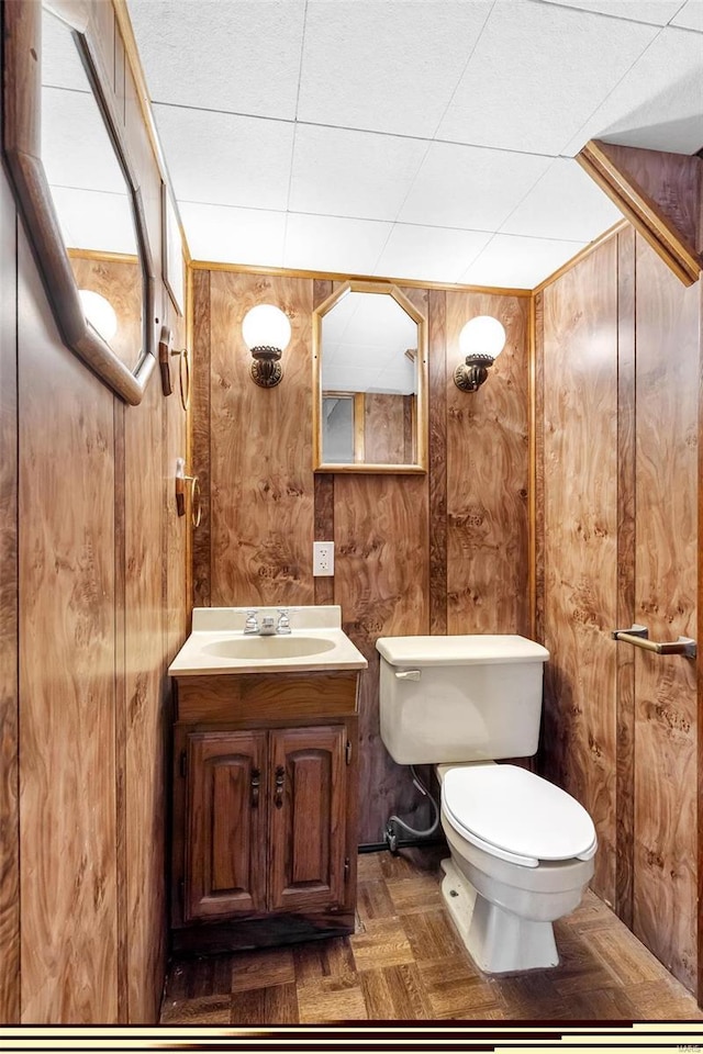 bathroom featuring vanity, toilet, and wood walls