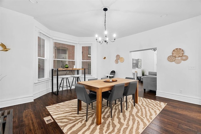 dining space with a notable chandelier and dark hardwood / wood-style flooring