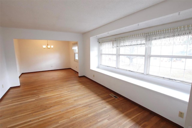 unfurnished room with a chandelier and light hardwood / wood-style flooring