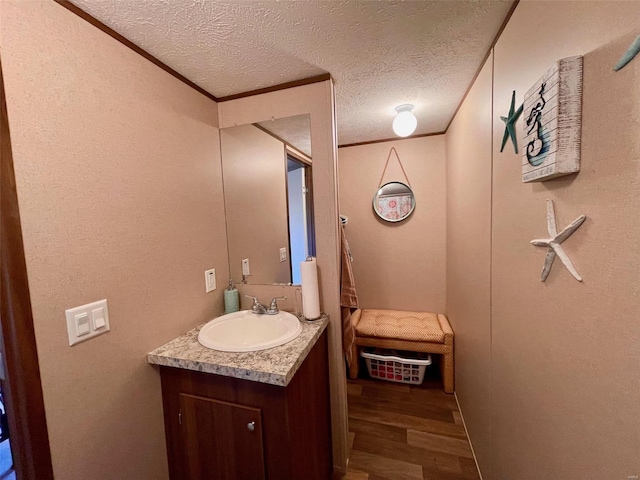 bathroom featuring vanity, hardwood / wood-style floors, a textured ceiling, and crown molding