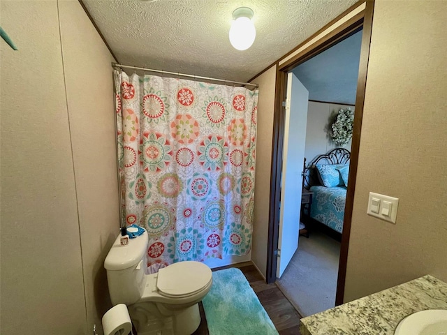 bathroom with vanity, hardwood / wood-style flooring, a shower with shower curtain, toilet, and a textured ceiling