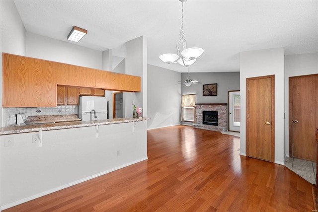 kitchen with a kitchen breakfast bar, white refrigerator, a fireplace, dark hardwood / wood-style flooring, and kitchen peninsula