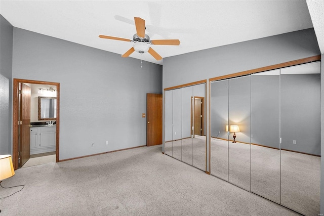 unfurnished bedroom with ceiling fan, ensuite bathroom, light carpet, and multiple closets