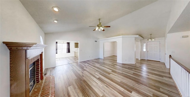 unfurnished living room featuring vaulted ceiling, ceiling fan, light hardwood / wood-style floors, and a fireplace