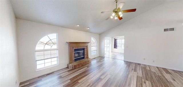 unfurnished living room featuring high vaulted ceiling, ceiling fan, a brick fireplace, and light hardwood / wood-style floors