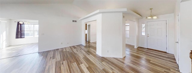 entryway featuring vaulted ceiling, a chandelier, and light hardwood / wood-style floors